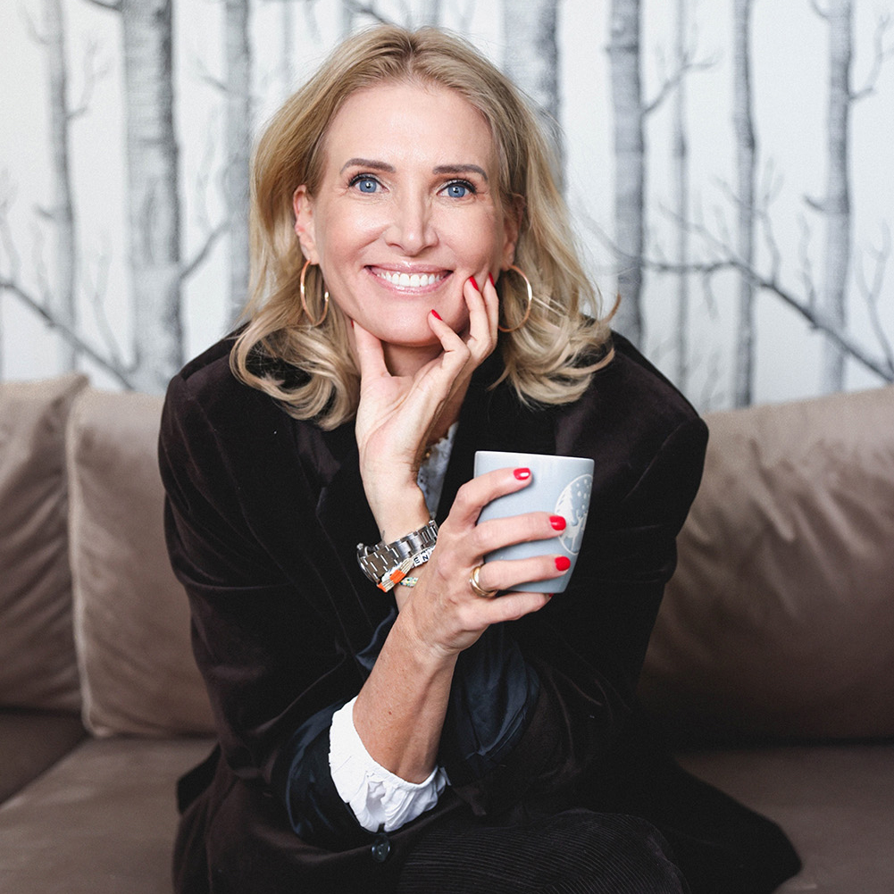 Christina, Co-Founderin von Make It Matter, Kommunikationsstrategin mit Fokus auf Markenkommunikation, Medienkompetenz und integrierte Kommunikationsstrategien, sitzt lächelnd mit einer Tasse in der Hand.