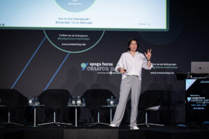 Kommunikationsstrategin von Make It Matter hält eine Keynote über Kommunikation, LinkedIn und strategische Markenführung auf einer Konferenzbühne.