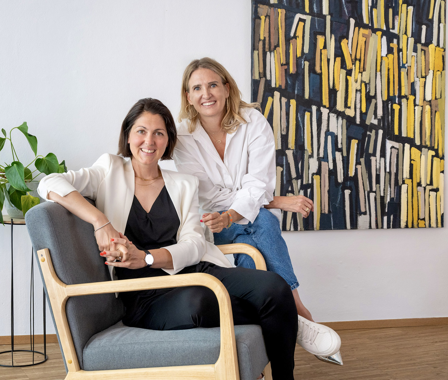 Die beiden Gründerinnen von Make It Matter, Lisa und Christina, sitzen gemeinsam in einem modernen Büro und lächeln – Symbol für Kommunikationsberatung, Teamarbeit und strategische Zusammenarbeit auf Augenhöhe.
